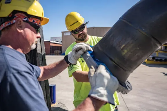Construction Workers Handling Pipe